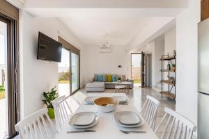 a white dining room with a table and chairs at Villa Sea La Vie in Kiotari