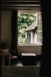 - une fenêtre dans une pièce avec une chaise et un tabouret dans l'établissement La Dime de Giverny - Chambres d'hôtes, à Giverny