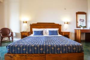a bedroom with a bed with a blue comforter at Hotel Village Suvaki in Pantelleria