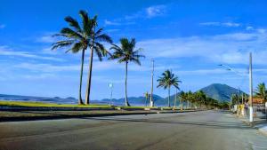 an empty street with palm trees and the ocean at Apartamento / Kitnetes in Peruíbe