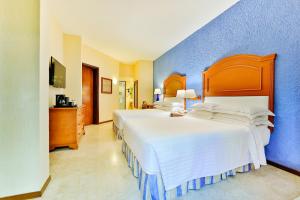 1 dormitorio con 2 camas y pared azul en Occidental Tucancún - All Inclusive, en Cancún