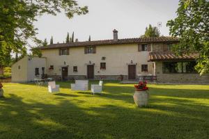 une grande maison avec des chaises blanches et une cour dans l'établissement Il Vignolino, à Barberino di Mugello