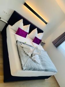 1 dormitorio con 1 cama con almohadas moradas y blancas en ImPuls | aparts, en Schladming