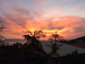 um pôr-do-sol do telhado de uma casa com uma palmeira em Magic Island Casas em Florianópolis