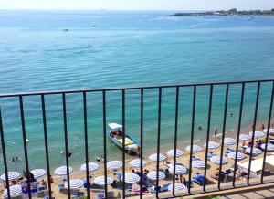 a beach with a bunch of umbrellas and people on the beach at Hotel Palladio in Giardini Naxos