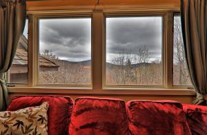 a couch sitting in front of a large window at Cozy,1 bedroom loft condo! Ski back trails, shuttle& Sports center Highridge E11 in Killington