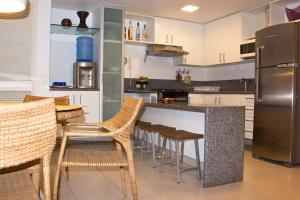 a kitchen with a counter with chairs and a refrigerator at Nannai Residence Muro Alto in Porto De Galinhas