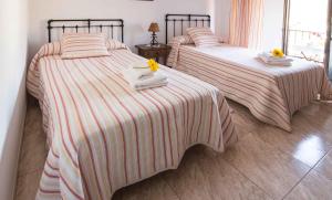 two beds in a bedroom with towels and flowers on them at Hostal Alba Taruta in Guadalupe