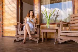 a woman sitting on a wooden bench in front of a window at Ladera Hotel in Turrialba