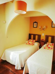 2 Betten in einem Zimmer mit einer gewölbten Wand in der Unterkunft Casa de Aldea La Pescal in La Pescal