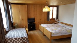 a bedroom with two beds and a television in it at Gasthof Rössli Gondiswil in Gondiswil