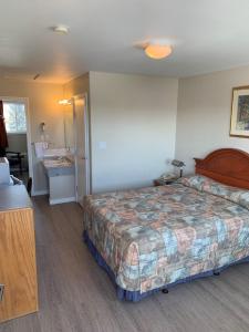 a hotel room with a bed and a bathroom at Red Deer Inn & Suites in Red Deer