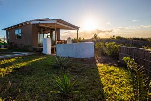 a small house in a yard with the sun setting at Casa Narinho in Praia do Tofo