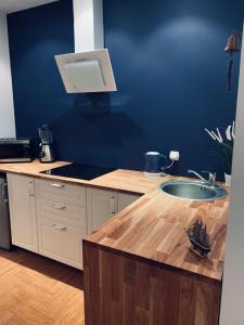 cocina con fregadero y pared azul en Apartament Il Capitano, en Gdynia