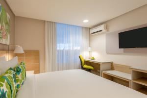 um quarto de hotel com uma cama, uma secretária e uma televisão em Mia Hotel Choco em Quibdó