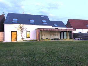 une maison blanche avec un toit noir et une cour dans l'établissement ma-tinée, à Beauvechain