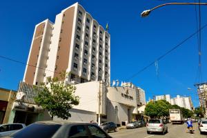 un edificio alto en una concurrida calle de la ciudad con coches en JB Palace Hotel, en Divinópolis