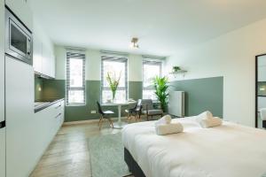a bedroom with a large white bed and a kitchen at The Card Room Green Studio in Antwerp