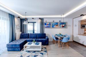 a living room with a blue couch and a table at Blue Port Gardenia in Dziwnów