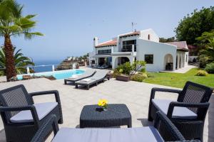 eine Terrasse mit Stühlen und Tischen sowie ein Haus in der Unterkunft Casa Las Rocas in Santa Úrsula
