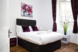 una camera da letto con un grande letto con cuscini viola di Montgomery Central Apartment a Edimburgo