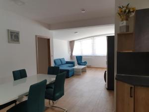 ein Wohnzimmer mit einem Tisch und blauen Stühlen in der Unterkunft Apartment Sebiell in Vrchlabí