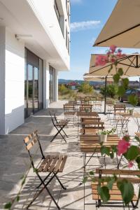 een patio met stoelen, tafels en parasols bij Hotel Aloha in Niš