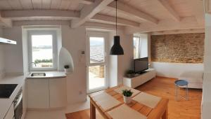 eine Küche und ein Wohnzimmer mit weißen Schränken und einer Ziegelwand in der Unterkunft Apartagal-Casas de Portochico, Foz in Foz