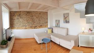 ein Wohnzimmer mit weißen Möbeln und einer Ziegelwand in der Unterkunft Apartagal-Casas de Portochico, Foz in Foz