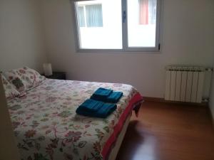 Un dormitorio con una cama con dos toallas azules encima. en Veluvi, en Puerto Madryn