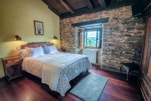 1 dormitorio con cama y pared de ladrillo en Apartamentos Rurales Casa Riveras, en Santa Eulalia de Oscos