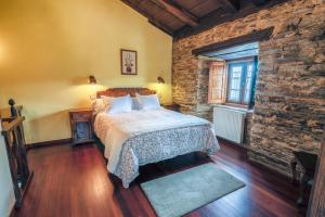 een slaapkamer met een bed en een stenen muur bij Apartamentos Rurales Casa Riveras in Santa Eulalia de Oscos