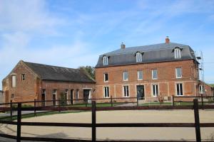 a large brick building with a fence in front of it at Ferme de Genève in Beaurevoir