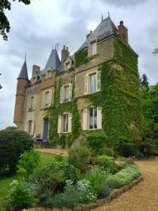 Ein altes Haus mit Efeu nebenbei in der Unterkunft France Petit Château in Loué