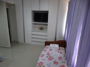 a room with a chair with a table and a tv at Pousada do Nei in Cabo Frio