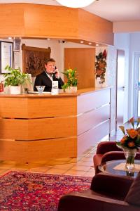 un hombre sentado en un mostrador hablando por celular en Hotel Rosenhof en Kerpen