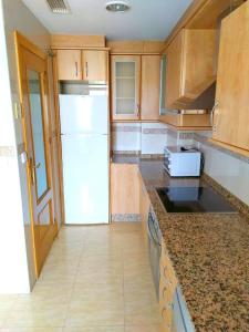 cocina con armarios de madera y nevera blanca en Apartamento Florencia en Murcia