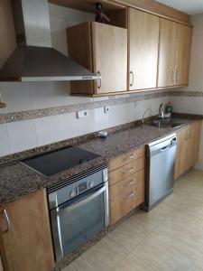 cocina con armarios de madera y horno con fogones en Apartamento Florencia en Murcia