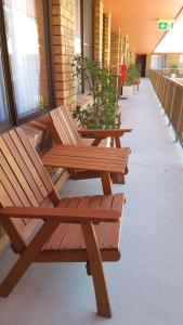 una fila de bancos de madera sentados en una pasarela en Royal Palms Motor Inn, en Coffs Harbour