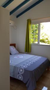 Cama en habitación con ventana en Planète Bleue Habitation mes DESIRS, en Beaurenom