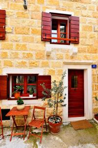 a building with red doors and a table and chairs at Sunny Bobica Apartments in Vodice