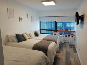2 Betten in einem Zimmer mit einem Tisch und einem Fenster in der Unterkunft Corazón de Buenos Aires in Buenos Aires