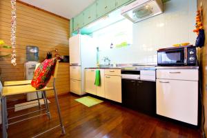 a kitchen with a stove and a sink and a chair at Bi ONE House 2F in Yomitan