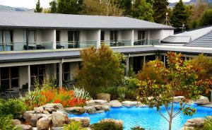 a large house with a pool and trees at Wai Ora Lakeside Spa Resort in Rotorua
