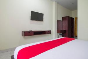 1 dormitorio con 1 cama y TV en la pared en RedDoorz at Benesari 2 Legian, en Kuta