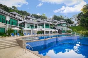 a resort pool with chairs and umbrellas at Royale Chulan Cherating Villa in Cherating