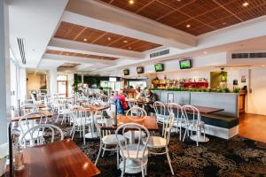 um restaurante com mesas e cadeiras e um bar em Coniston Hotel Wollongong em Wollongong