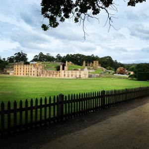 a large building in a field with a fence at Blossoms on the Bay - Nubeena in Nubeena