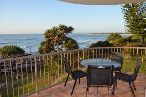 a patio with a table and chairs and the ocean at Pandanus Shores Kings Beach in Caloundra