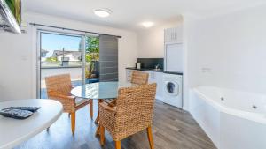 
a kitchen with a table, chairs and a refrigerator at Adrift Apartments in Yamba
